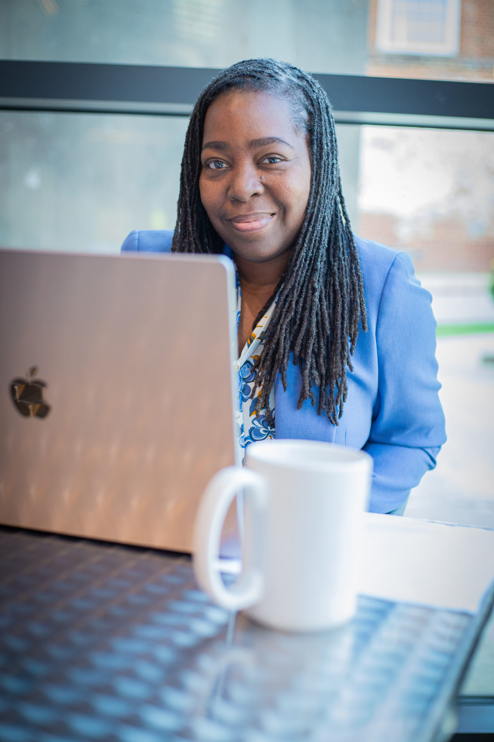 Michelle sitting at a table with her laptop, waiting to join a coaching call with a client working on burnout recovery