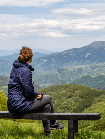 A leader pausing on a mountain path, reflecting on their resilience and personal growth